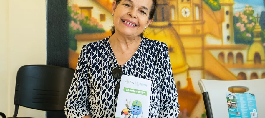 A woman holds a SEAPAL information leaflet while seated in front of a Puerto Vallarta mural.