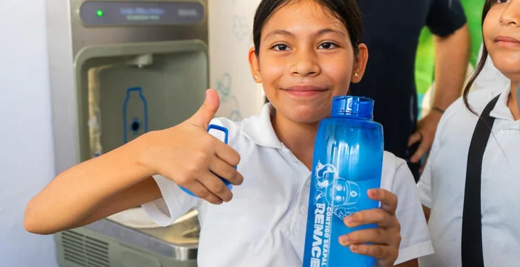 A student holds a reusable water bottle beside the new drinking fountain at Cuauhtémoc Elementary School.