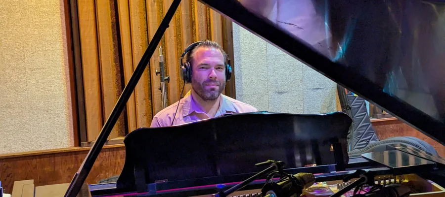 Joe Schlesinger wearing headphones at a grand piano during the Family Dinner recording sessions.