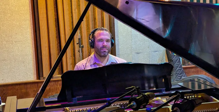 Joe Schlesinger wearing headphones at a grand piano during the Family Dinner recording sessions.